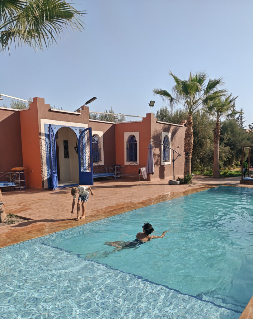 Piscine de Sajada devant une maison aux portes bleues et des palmiers