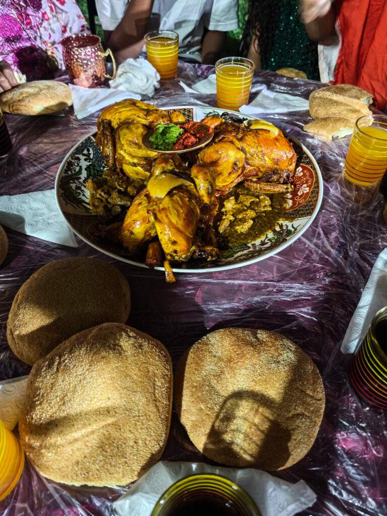 Grand plat de poulet à partager, entouré de pains, lors de la soirée chez Saïda et Gérard